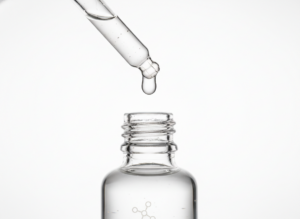 Elegancka butelka z kroplomierzem, z idealną kroplą koreańskiego serum do twarzy, na białym tle.